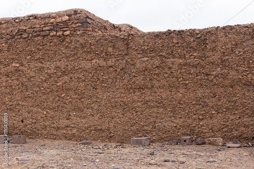 Obraz na płótnie The earthy tones and irregular textures of this mud wall, built using age-old techniques, bring a sense of authenticity to the Moroccan countryside. w salonie