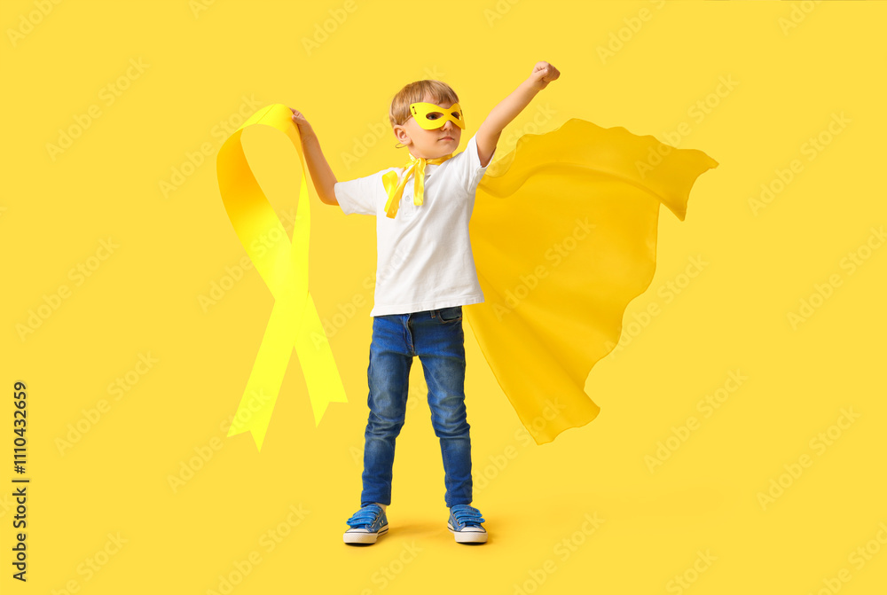 Little boy dressed as superhero with gold ribbon on color background. Childhood cancer awareness concept Little boy dressed as superhero with gold ribbon on color background. Childhood cancer awareness concept