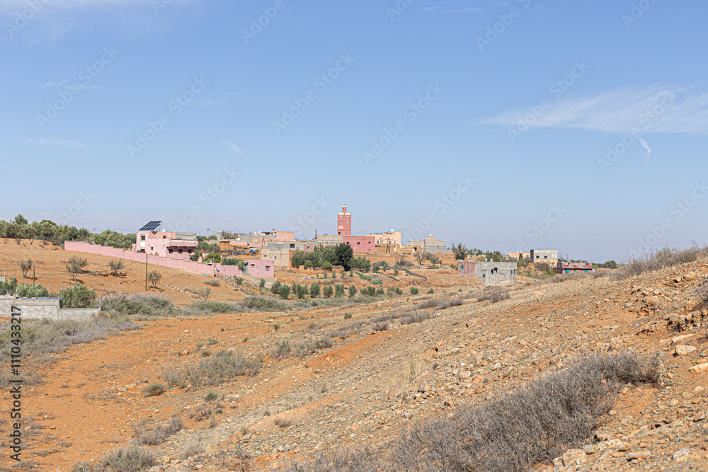 A tranquil village set in the Moroccan desert, with a blend of mud-brick homes and a prominent minaret. A tranquil village set in the Moroccan desert, with a blend of mud-brick homes and a prominent minaret.