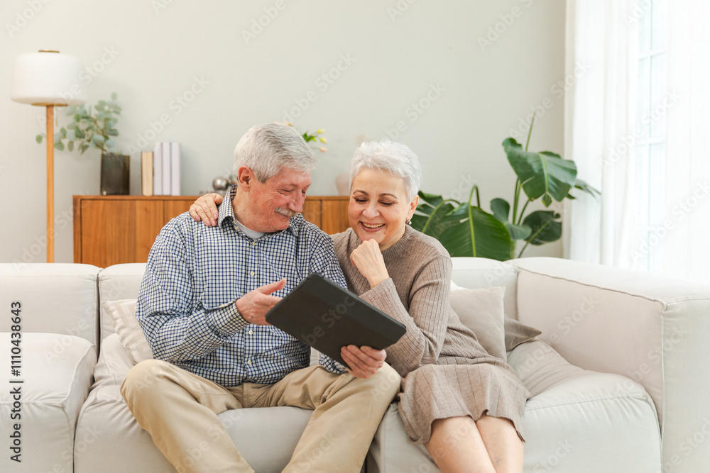 Senior old couple with tablet watching video online. Husband wife spending time together at home. Happy modern mature senior couple using tablet for family entertainment. Old people modern technology Senior old couple with tablet watching video online. Husband wife spending time together at home. Happy modern mature senior couple using tablet for family entertainment. Old people modern technology