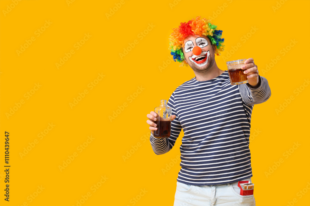 Young man as alcoholic clown with bottle of whiskey and cigarettes on yellow background Young man as alcoholic clown with bottle of whiskey and cigarettes on yellow background