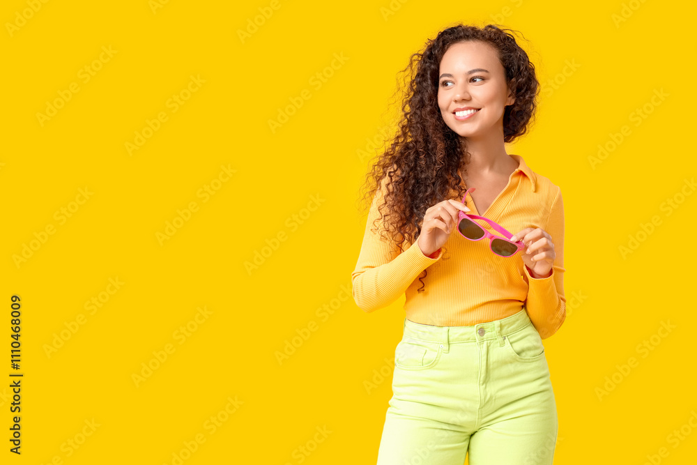 Beautiful African-American woman with sunglasses on yellow background Beautiful African-American woman with sunglasses on yellow background