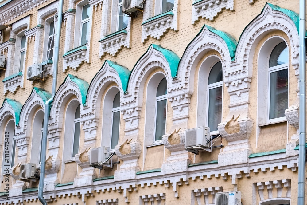Fototapeta premium Traditional ornate facade with row of arched windows on wall of old residential building with ornamental details in Moscow, Russia. Architecture and city street background
