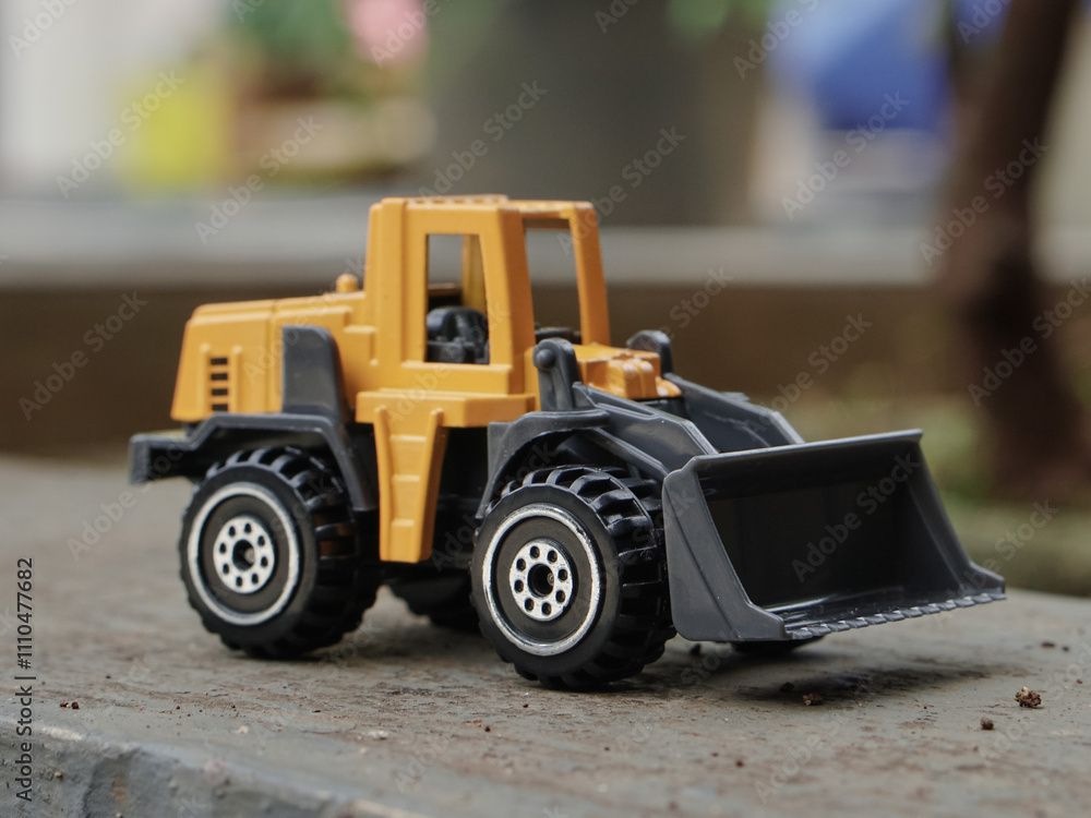 Yellow wheel loader or bulldozer toy outdoor with blurred background. construction image concept. side view photograph Yellow wheel loader or bulldozer toy outdoor with blurred background. construction image concept. side view photograph