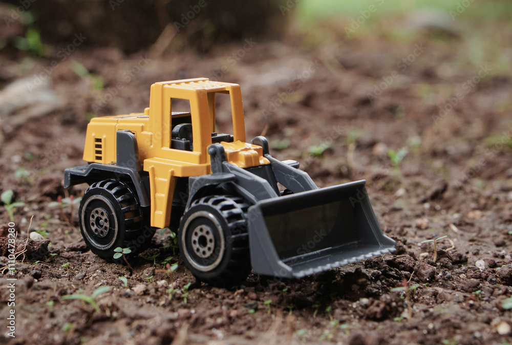 Yellow wheel loader or tractor toy on soil or ground background. construction image concept with heavy equipment. Yellow wheel loader or tractor toy on soil or ground background. construction image concept with heavy equipment.