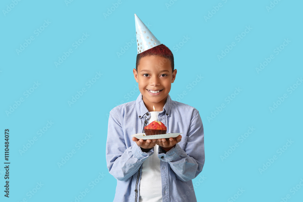 Cute little African-American boy in party hat with birthday cake on blue background Cute little African-American boy in party hat with birthday cake on blue background