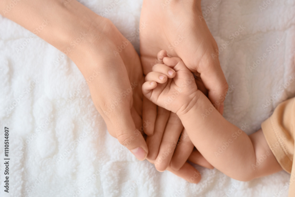 Mother holding her little baby's hand on bed, top view Mother holding her little baby's hand on bed, top view