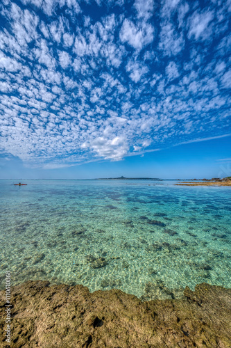 Crystal clear waters of Bise Beach, Motobu District, Okinawa main island. White sand beach with coral outcrops and small islands offshore.