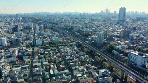 4K aerial view of Tokyo’s residential area. Roads and railways intersect under clear skies, capturing urban life.