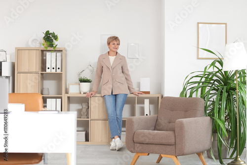 Mature businesswoman near shelf unit in office