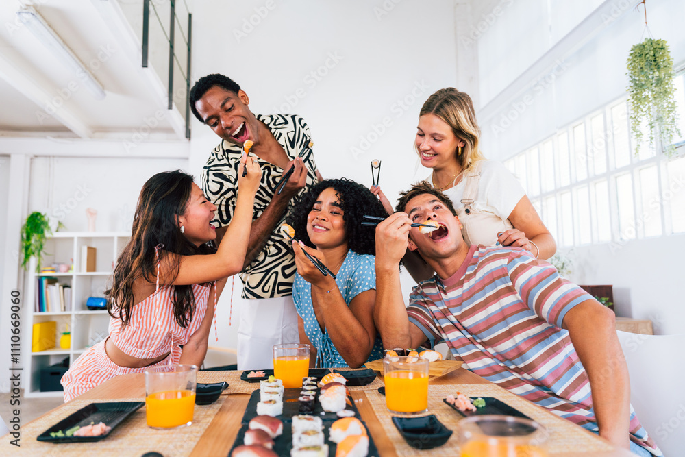 Obraz premium Multiethnic group of young friends meeting at home and eating sushi