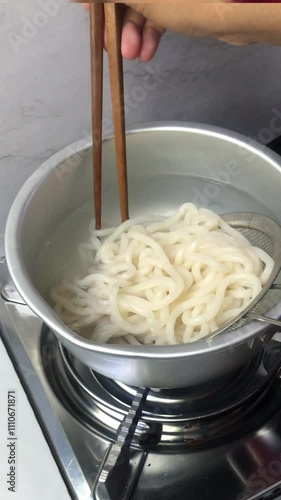 Boil instant noodles by stirring with chopsticks