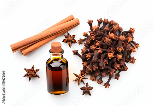 The image showcases cinnamon sticks, star anise, cloves, and a bottle of essential oil, highlighting aromatic spices commonly used in cooking and fragrance. photo