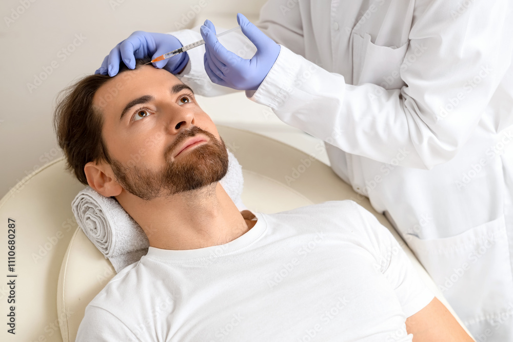 Young man receiving injection for hair growth on couch at trichologist's office Young man receiving injection for hair growth on couch at trichologist's office