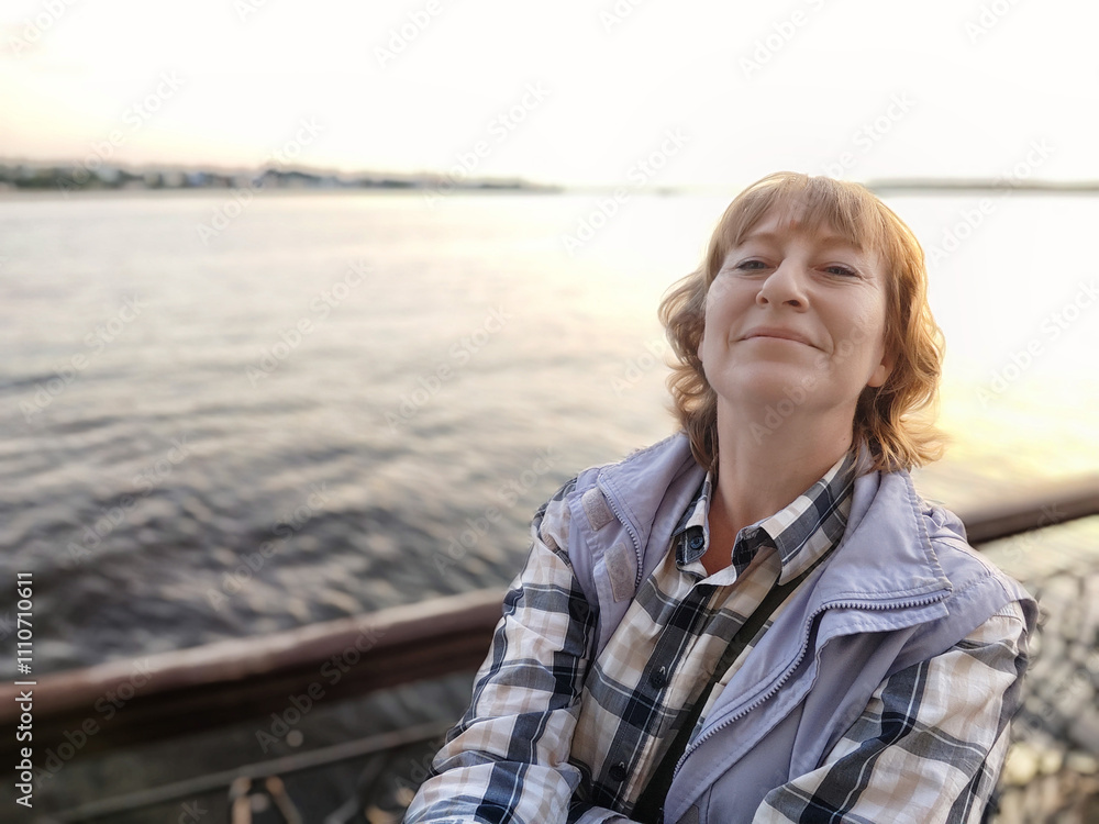 Fototapeta premium Middle aged woman enjoys a serene moment by the water during a travel excursion