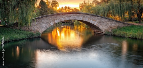 Stone arch bridge over a quiet river with willow trees lining the banks and warm sunset light reflecting in the water.