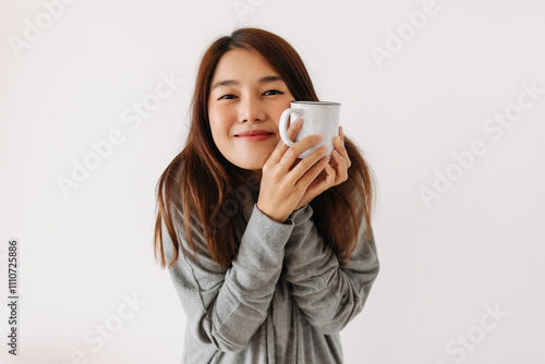 Happy asian woman wear grey sweater, holding white cup with smiling face in winter, drinking hot water coffee, making warm, isolated over white background wall.