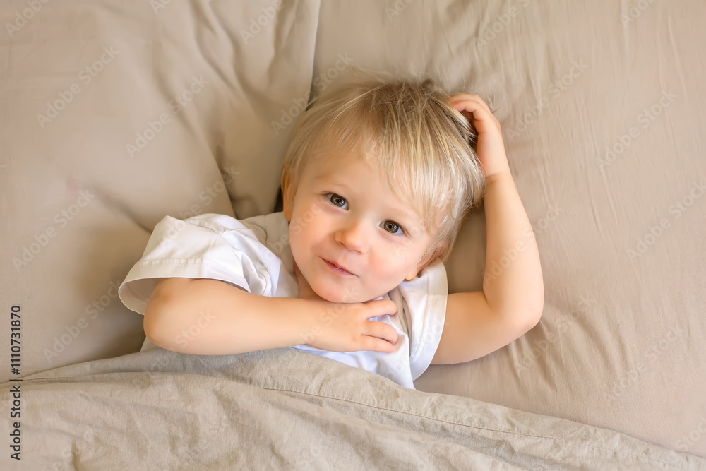 a young boy with blonde hair is laying on a couch. a young boy with blonde hair is laying on a couch.