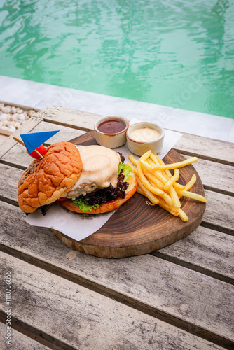 Pork burger served with cheeses and french fries place on wooden boad