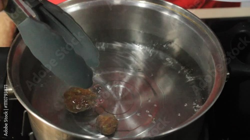 Someone boils meatballs. Cook the meatballs in a pan