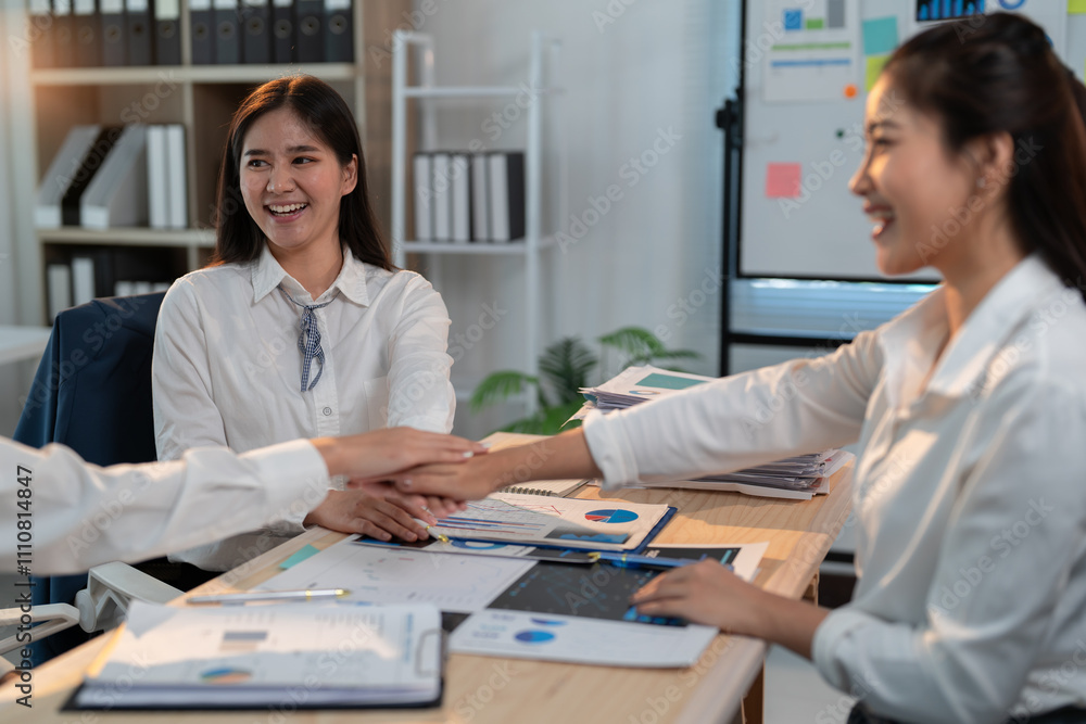 Fototapeta premium Diverse asian businesswomen celebrate successful project, showing teamwork and unity in office. Smiling, confident, happy