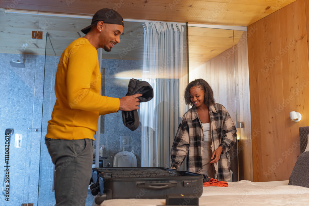African American couple packing wardrobe in a suitcase preparing to leave hotel room after relaxing vacation. Travel lifestyles concept. African American couple packing wardrobe in a suitcase preparing to leave hotel room after relaxing vacation. Travel lifestyles concept.