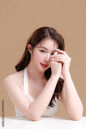 Pretty Asian woman model perfect clear fresh skin smile on isolated beige background. Portrait female beauty blogger make up artist in studio. Skincare, plastic surgery, spa concept.