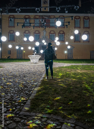 Billede på lærred Brixen, South Tyrol - 2024: A girl standing taking photos at the Water Light Festival inside the historic center of the old city of Brixen (Bressanone) in South Tyrol - Sudtirol - Alto Adige
