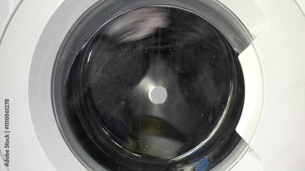 Close-up shot of a washing machine in motion, showcasing spinning laundry through the transparent door, capturing the dynamic energy of modern home appliances. Close-up shot of a washing machine in motion, showcasing spinning laundry through the transparent door, capturing the dynamic energy of modern home appliances.