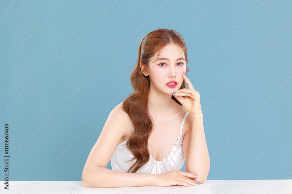 Pretty Asian beauty woman curly long hair with Korean makeup glowing face and healthy facial skin portrait smile on isolated blue background. Pretty Asian beauty woman curly long hair with Korean makeup glowing face and healthy facial skin portrait smile on isolated blue background.