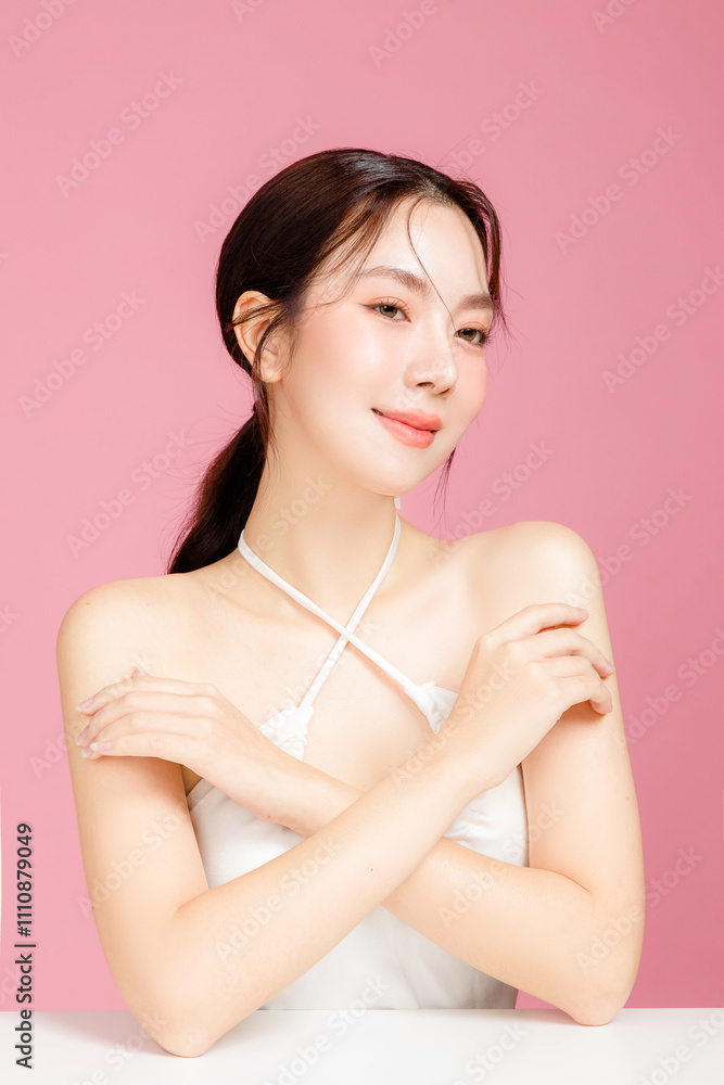 Young Asian woman gathered in ponytail with natural makeup on face have plump lips and clean fresh skin wearing white camisole on isolated pink background. Portrait of cute female model in studio. Young Asian woman gathered in ponytail with natural makeup on face have plump lips and clean fresh skin wearing white camisole on isolated pink background. Portrait of cute female model in studio.