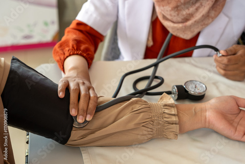 A healthcare professional measures a patient's blood pressure with a manual sphygmomanometer, emphasizing medical care, routine checkups, and the importance of patient wellness. photo