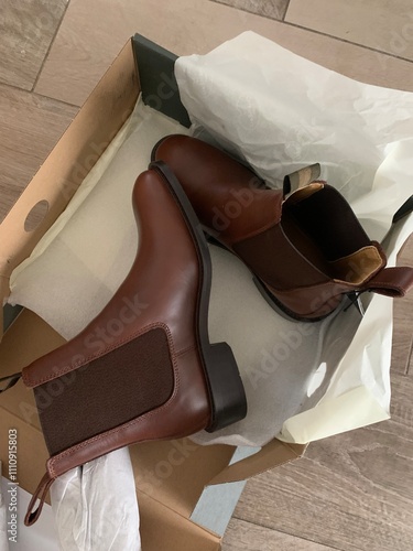 Close-up of brand-new brown leather boots in a shoe box with protective wrapping. Stylish and elegant footwear for formal or casual occasions, showcasing craftsmanship and timeless design. photo