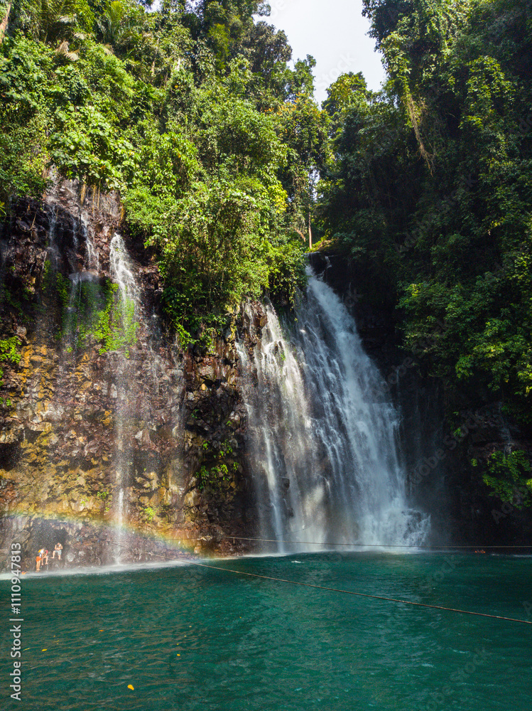 Fototapeta premium Rainbow over green plunge pool. Tinago Falls. Lanao del Norte. Philippines.