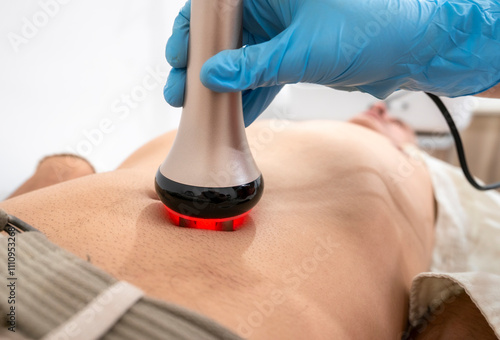 A man is getting a massage with a red light on his stomach