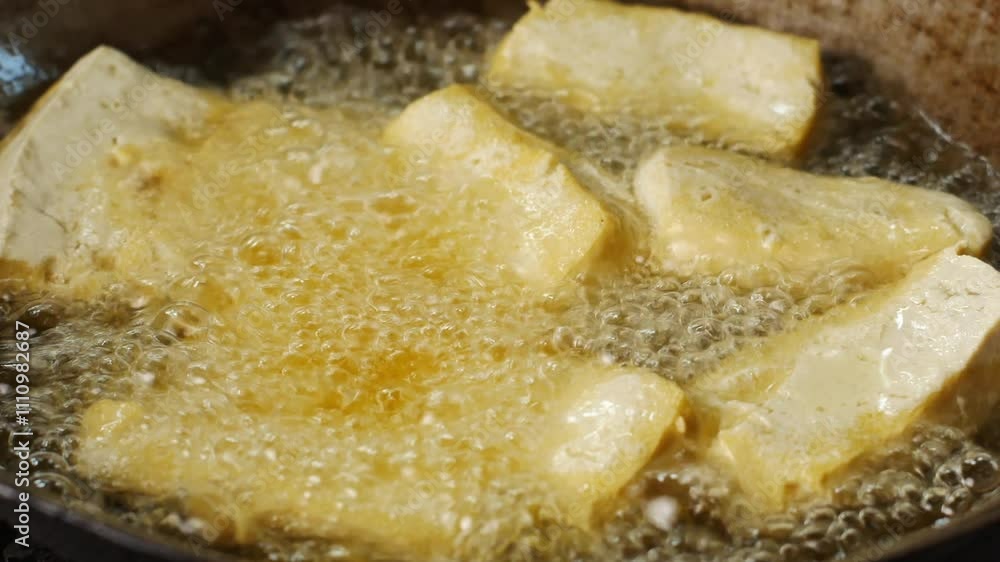 4k video of frying tofu in a pan filled with cooking oil. 4k video of frying tofu in a pan filled with cooking oil.
