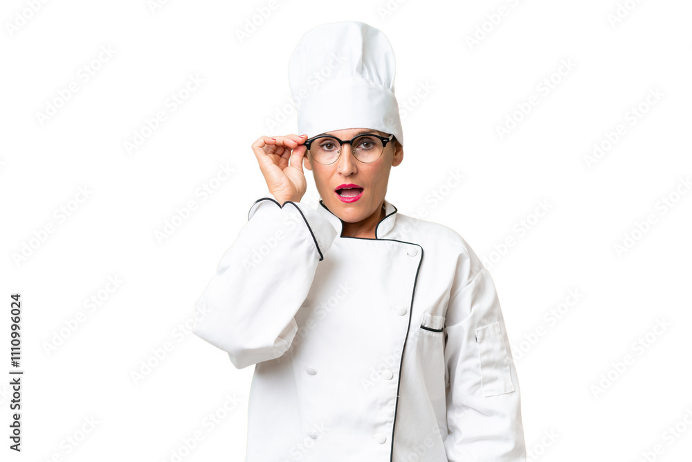 Middle-aged chef woman over isolated background with glasses and surprised Middle-aged chef woman over isolated background with glasses and surprised