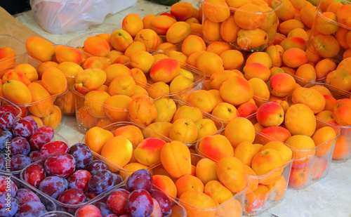 ripe orange apricots and plums for sale at the neighborhood market stall during the summer photo