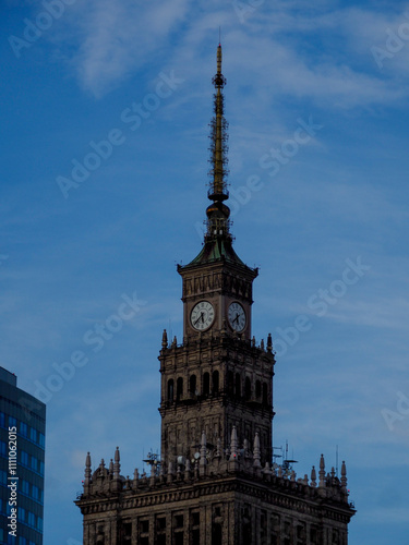 Historic Clock Tower with Spire Against Blue Sky in Urban Setting