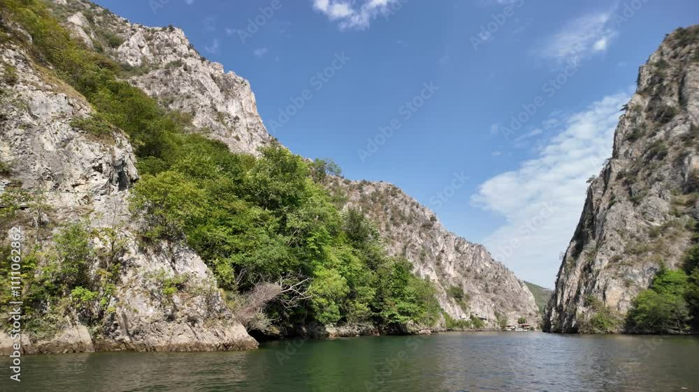 Tourists enjoy peaceful boat trip on serene Matka lake, surrounded by breathtaking cliffs and lush greenery of Matka Canyon in Macedonia Tourists enjoy peaceful boat trip on serene Matka lake, surrounded by breathtaking cliffs and lush greenery of Matka Canyon in Macedonia