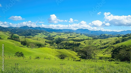 Lush Green Rolling Hills Under a Bright Blue Sky with Fluffy White Clouds and Majestic Mountains in the Background of a Serene Landscape