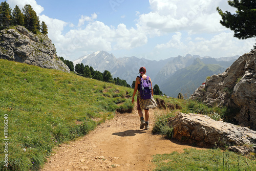 woman hiker with backpack walking on dirt trail in mountains during spring