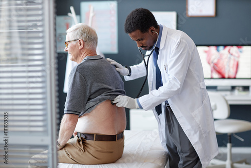 Принти на полотні Side view of African American doctor using stethoscope and listening to heart an