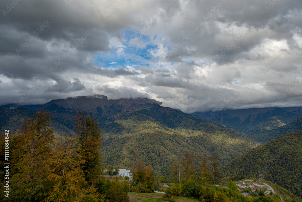 Cloudy evening at a picturesque mountain resort in autumn, heavy thunderclouds. Mountain peaks are shrouded in dark clouds. Early autumn, picturesque mountain ranges Cloudy evening at a picturesque mountain resort in autumn, heavy thunderclouds. Mountain peaks are shrouded in dark clouds. Early autumn, picturesque mountain ranges