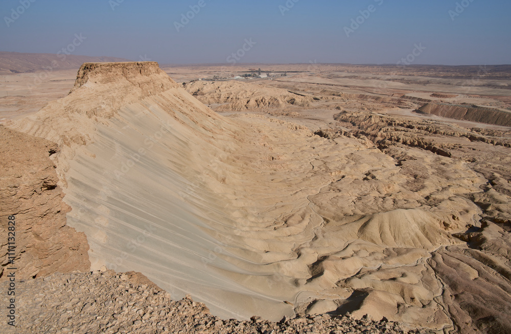 Fototapeta premium Unique desert landscape as seen from the hiking path in the first summit of Mount Zin. The view on the second summit of the mount that is like a flat table, and Zin phosphate plant in the background.