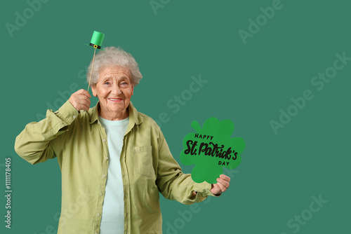 Happy senior woman holding festive postcard with text HAPPY ST. PATRICK'S DAY on green background photo