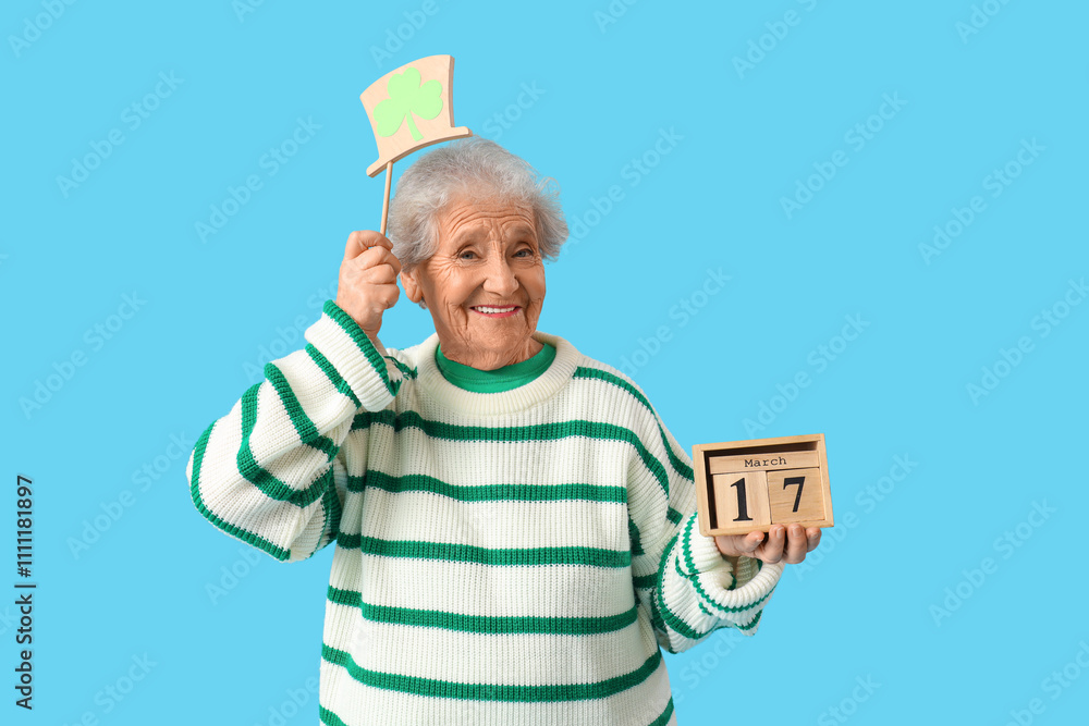 Happy senior woman with decor and calendar for St. Patrick's Day celebration on blue background Happy senior woman with decor and calendar for St. Patrick's Day celebration on blue background