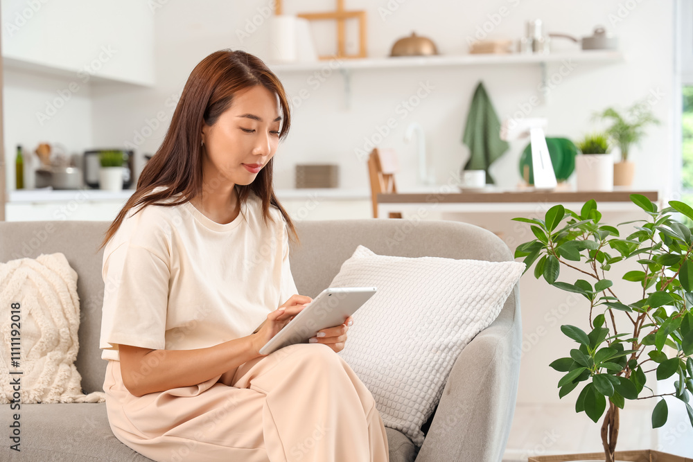 Young Asian businesswoman working with tablet computer on sofa at home Young Asian businesswoman working with tablet computer on sofa at home