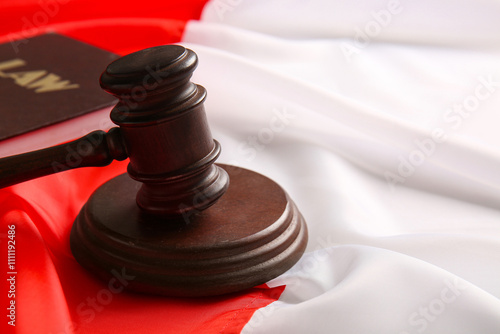 Judge's gavel and law book on flag of Poland, closeup photo