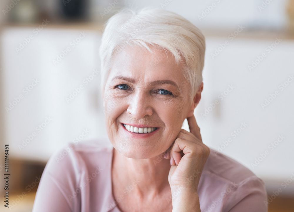 Attractive aged business lady smiling at camera at home, touching her ear, flirting Attractive aged business lady smiling at camera at home, touching her ear, flirting